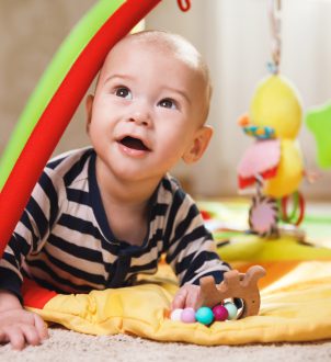 Cute little baby is playing on the activity mat